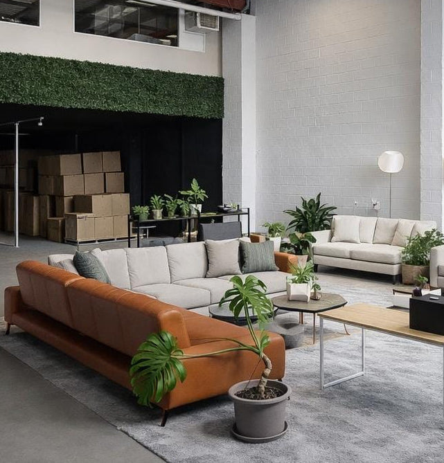 Modern living room with gray and orange sofas, coffee tables, and decorative plants.